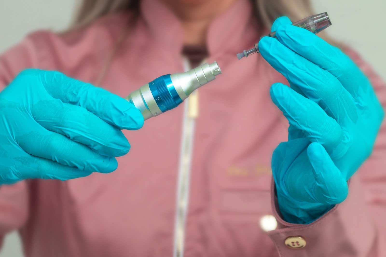 Mãos com luvas montando a caneta de microagulhamento capilar antes do procedimento